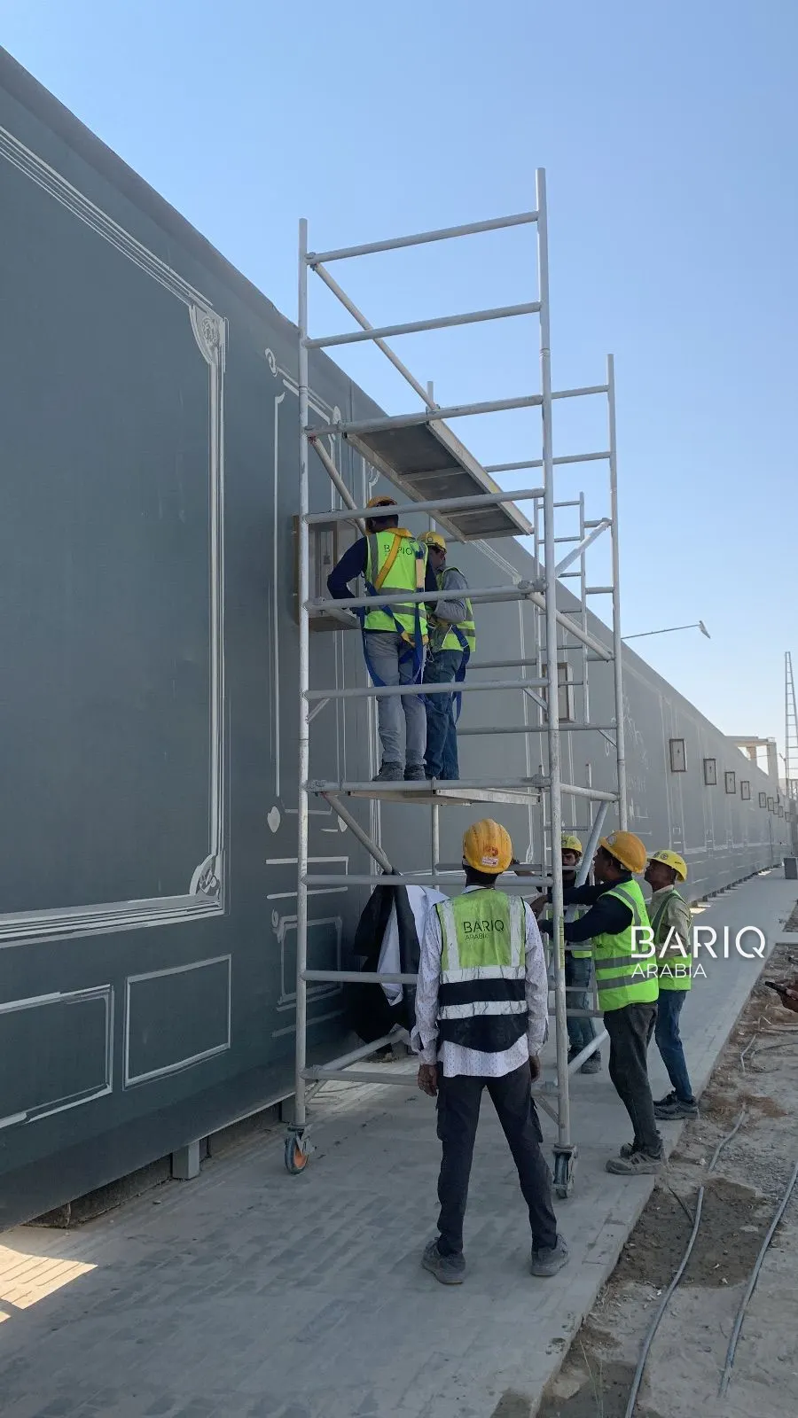 Bariq Arabia crew installing hoarding banners from a scaffold with safety gear